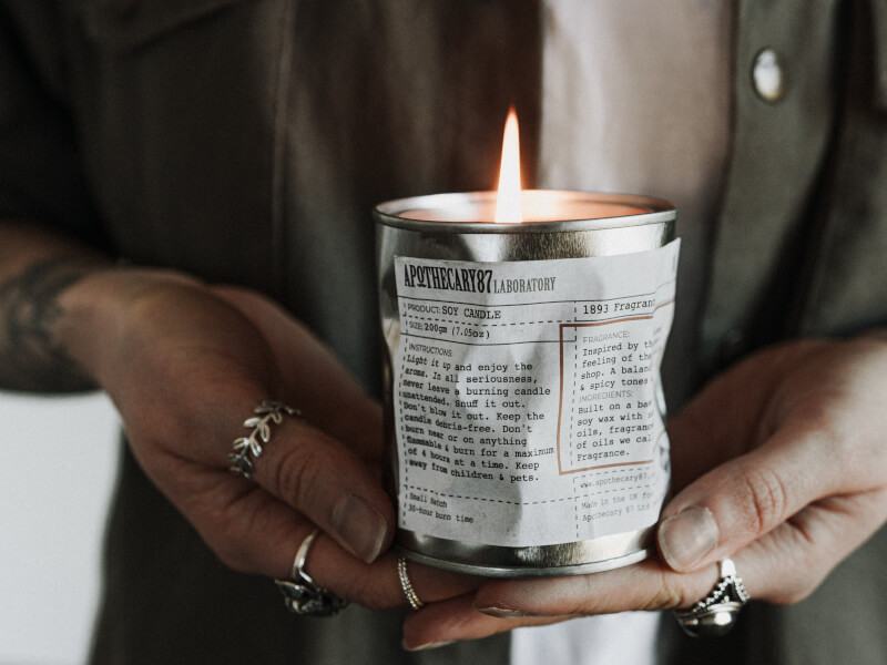 A lit handmade candle in a tin
